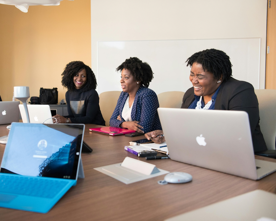 Image of successful African-American women setting in a board room with their laptops brainstorming the growth and success of Glass Web Services